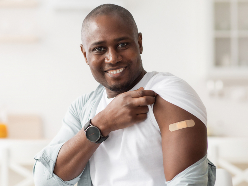 man smiling while showing the bandaid on his arm