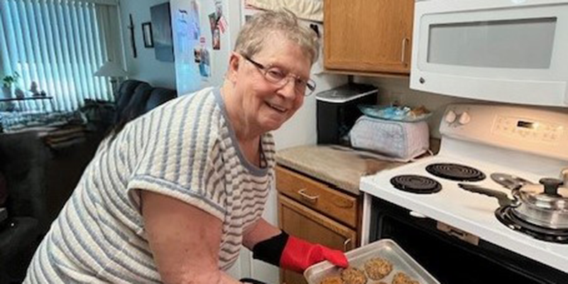 Jeanette Friedt taking out a pan of cookies from her oven.